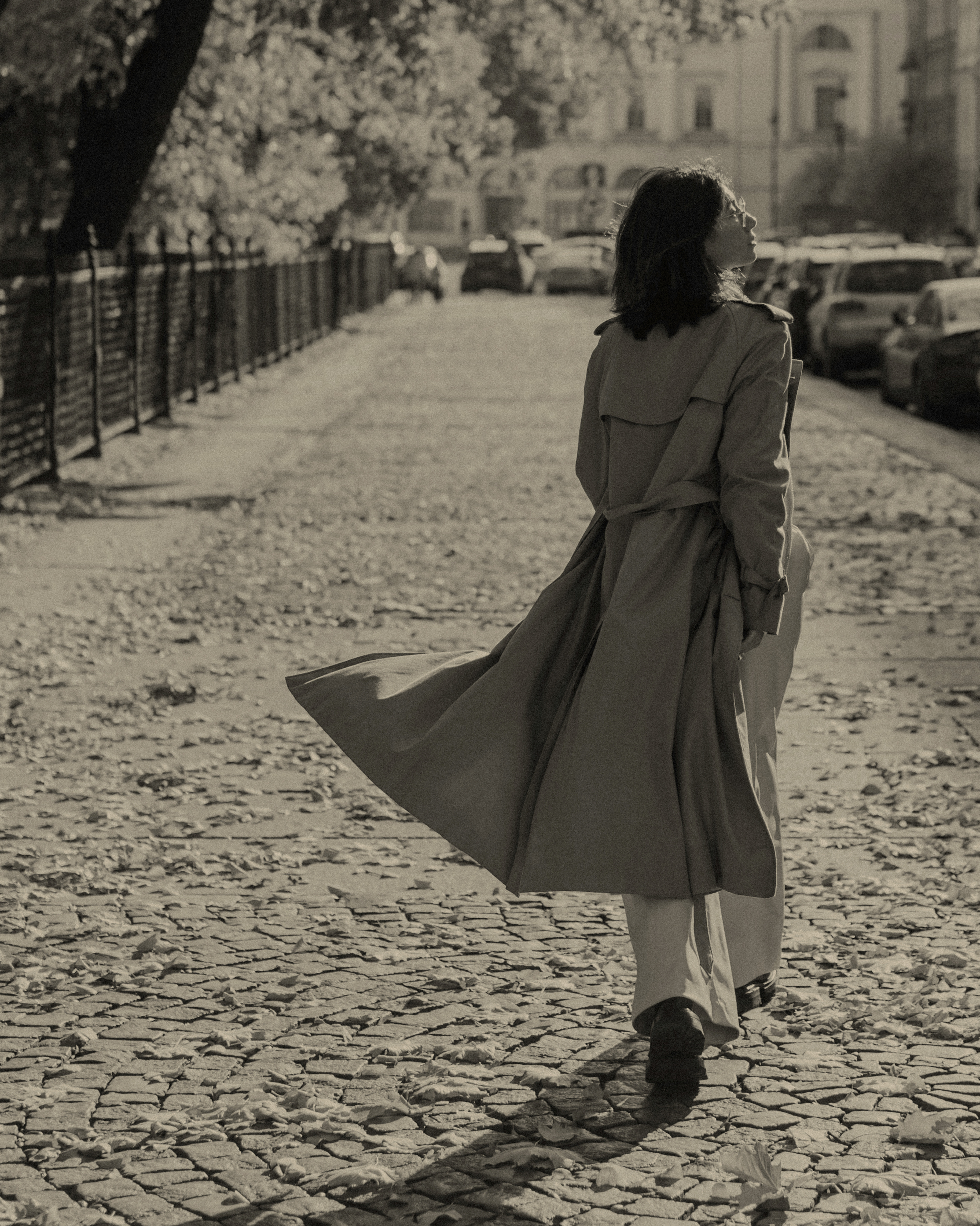 a lady walking along a street with a long jacket